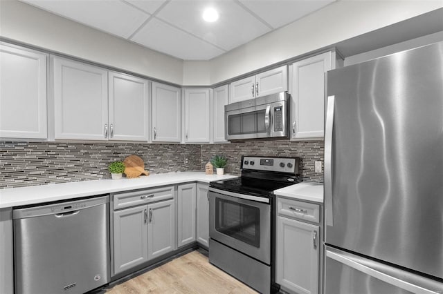 kitchen featuring tasteful backsplash, stainless steel appliances, gray cabinetry, and light wood-type flooring