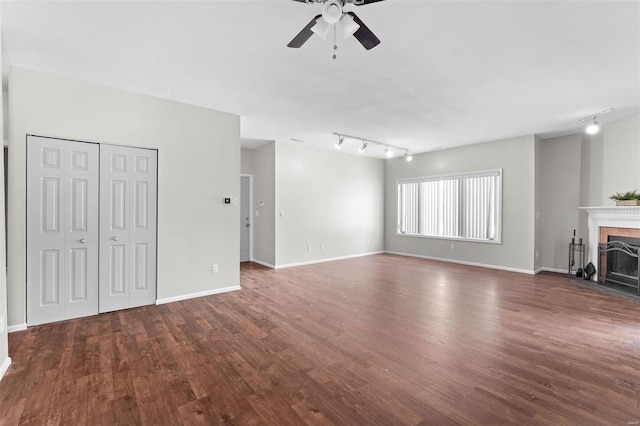 unfurnished living room featuring dark wood-type flooring, rail lighting, and ceiling fan