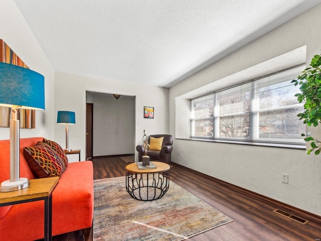 living area with visible vents, a textured ceiling, and wood finished floors