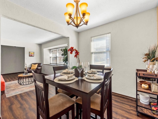 dining space with wood finished floors, baseboards, an inviting chandelier, a textured ceiling, and a textured wall