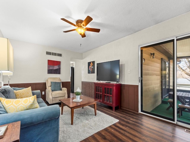 living room featuring visible vents, a wainscoted wall, a textured ceiling, wood finished floors, and ceiling fan