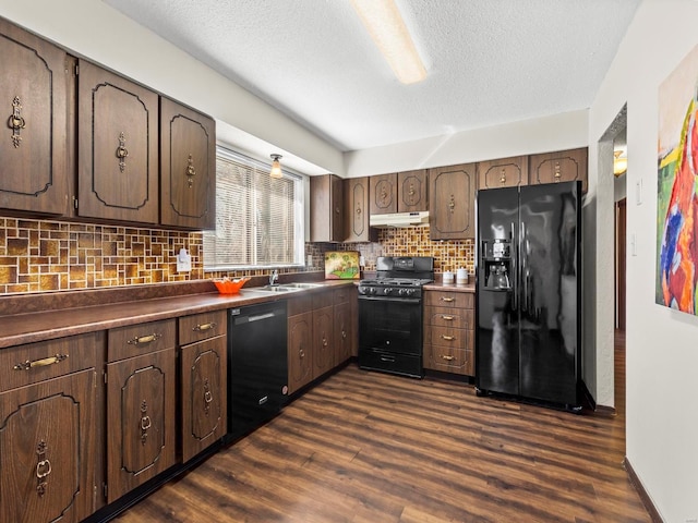 kitchen featuring under cabinet range hood, backsplash, black appliances, and dark wood-style floors