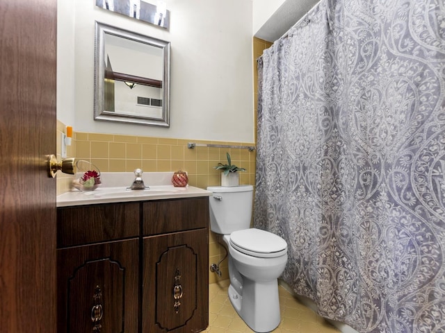 bathroom with vanity, wainscoting, tile walls, toilet, and tile patterned floors