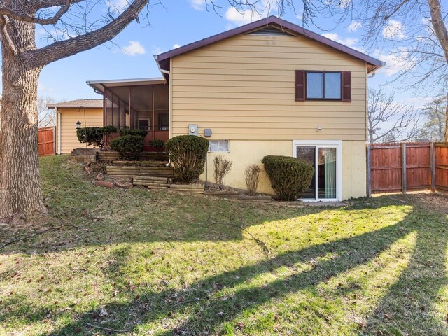 back of property with a yard, fence, and a sunroom