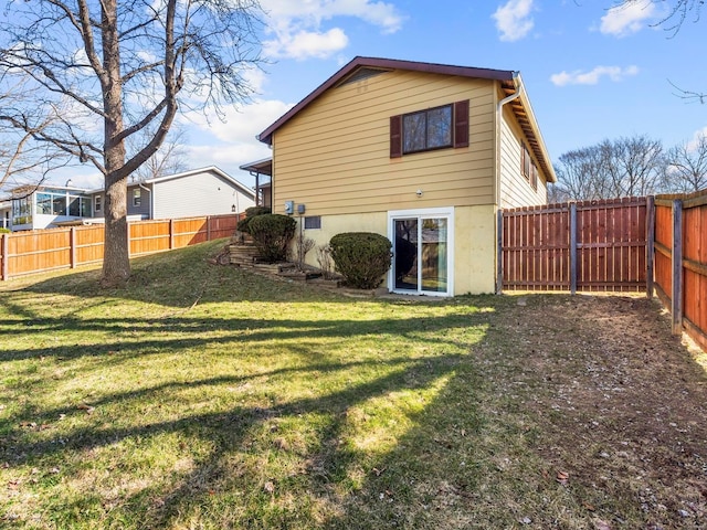 rear view of house with a yard and a fenced backyard