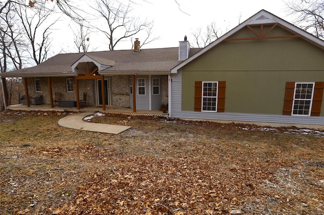 rear view of house with stone siding and a chimney