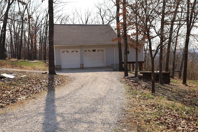 view of front facade featuring an attached garage, driveway, and roof with shingles