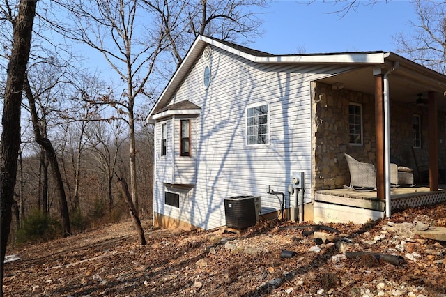 view of side of home with cooling unit and stone siding