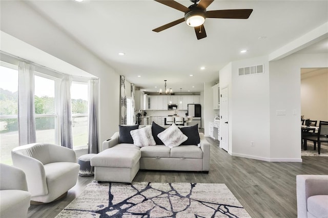 living room with ceiling fan with notable chandelier and wood-type flooring