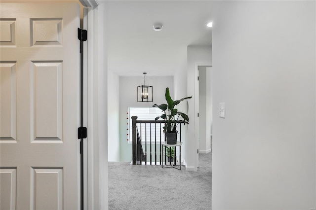 corridor with carpet floors and a chandelier