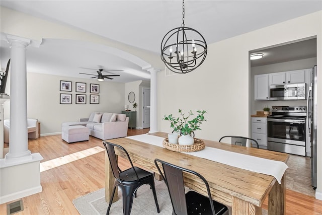 dining space featuring arched walkways, ceiling fan with notable chandelier, light wood-type flooring, and decorative columns