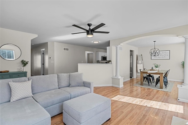 living area featuring decorative columns, arched walkways, visible vents, and light wood finished floors