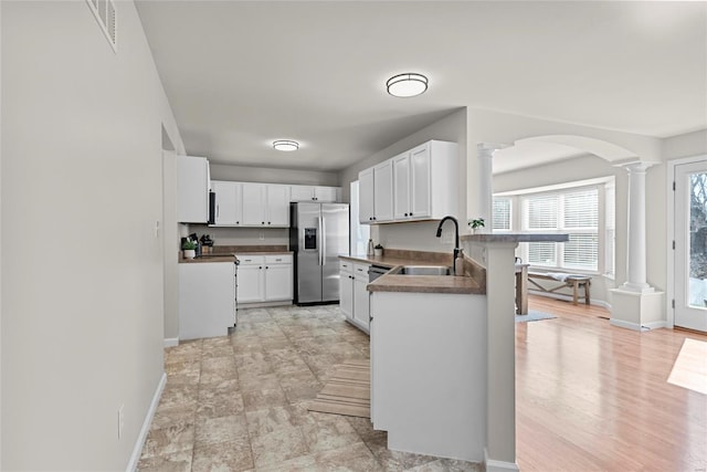 kitchen featuring visible vents, stainless steel fridge with ice dispenser, arched walkways, ornate columns, and a sink