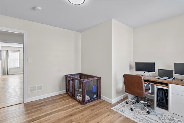 office area with baseboards, visible vents, and light wood finished floors