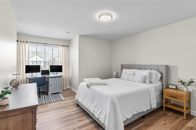 bedroom featuring visible vents, baseboards, and light wood finished floors