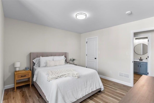 bedroom featuring light wood-style flooring, baseboards, visible vents, and a sink