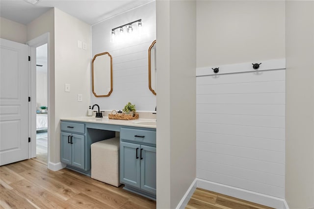 full bathroom featuring double vanity, a sink, baseboards, and wood finished floors