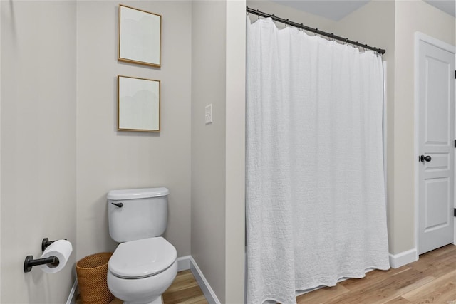 bathroom featuring a shower with curtain, toilet, wood finished floors, and baseboards