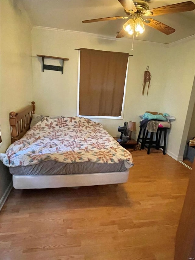 bedroom featuring crown molding, wood-type flooring, and ceiling fan