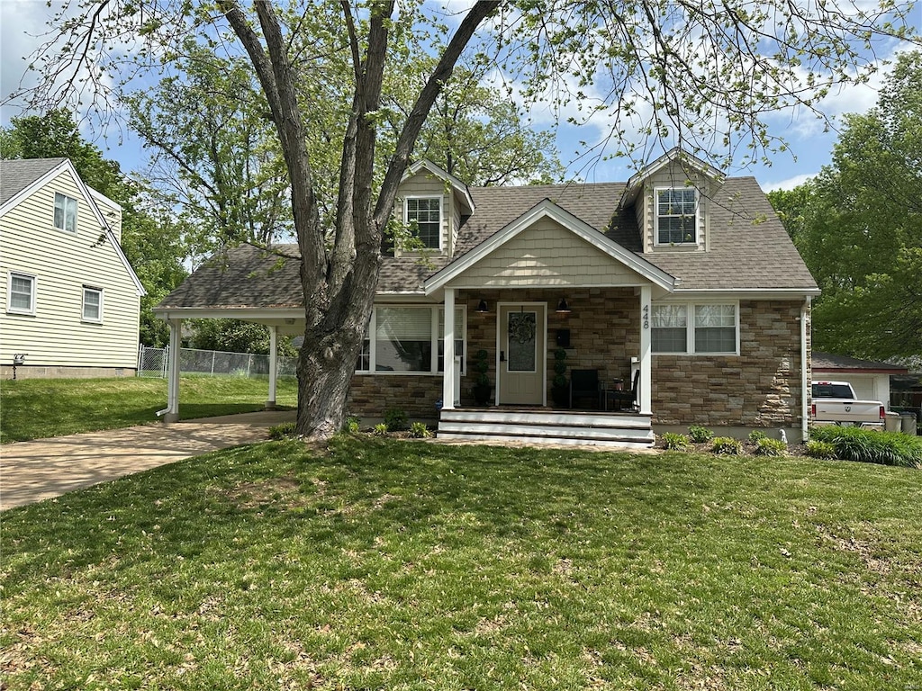 view of front of home with fence, roof with shingles, stone siding, a porch, and driveway