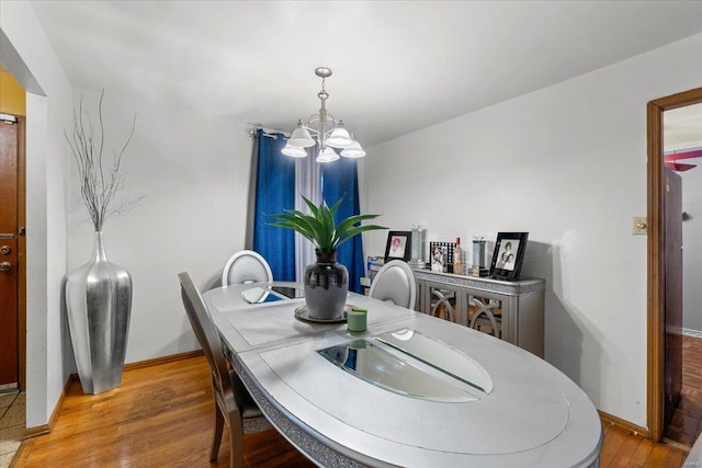 dining space with baseboards, a notable chandelier, and wood finished floors