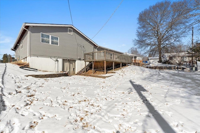 snow covered rear of property featuring a deck and stairs