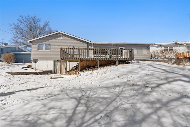 snow covered back of property with a wooden deck