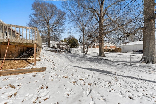 yard covered in snow with a deck and fence