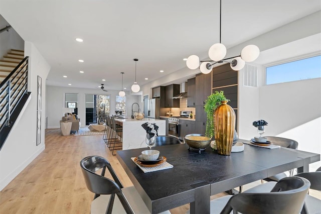 dining room with light wood-style floors, recessed lighting, a wealth of natural light, and stairway