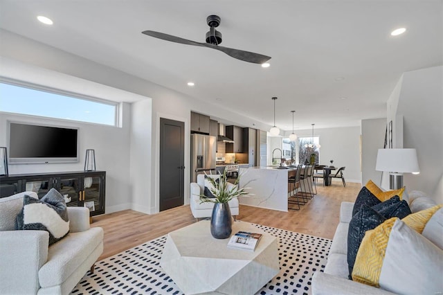 living area with light wood finished floors, a ceiling fan, a wealth of natural light, and recessed lighting