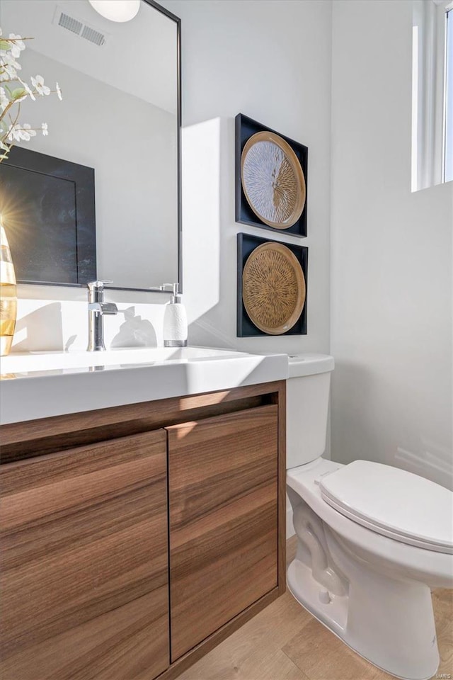 half bathroom with toilet, vanity, and visible vents