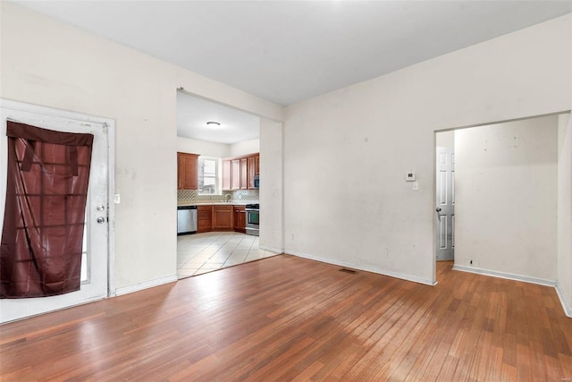 unfurnished living room featuring light wood-style flooring and baseboards