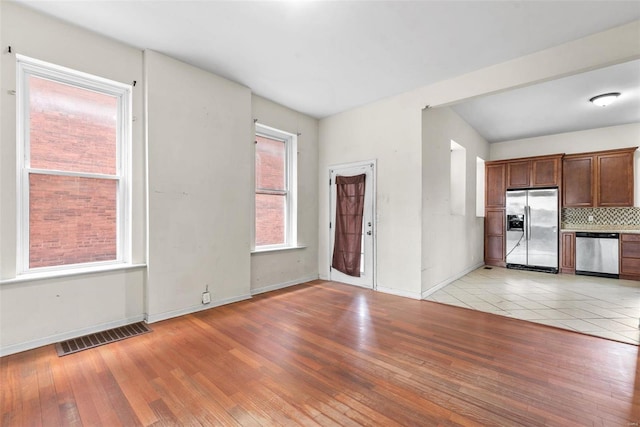 unfurnished living room featuring light wood-type flooring, baseboards, and visible vents