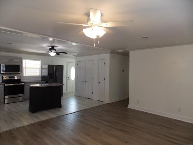 kitchen with stainless steel appliances, a kitchen island, ceiling fan, wood-type flooring, and crown molding