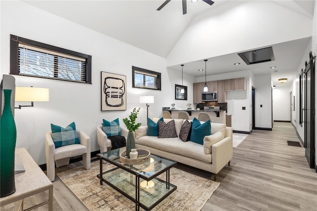 living area with light wood finished floors, recessed lighting, ceiling fan, high vaulted ceiling, and baseboards