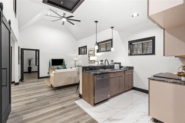 kitchen with a barn door, a sink, dark stone counters, dishwasher, and a peninsula