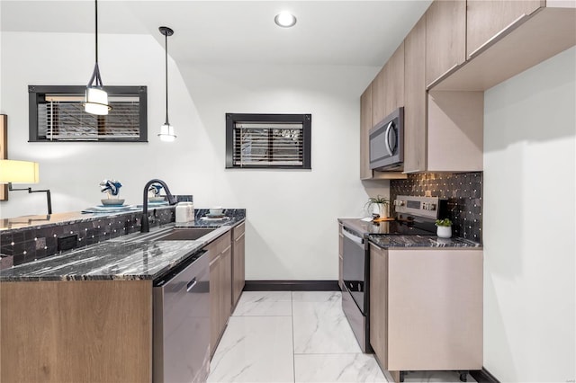 kitchen featuring stainless steel appliances, marble finish floor, a sink, and dark stone countertops