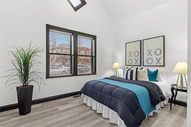 bedroom with light wood-type flooring, visible vents, lofted ceiling, and baseboards