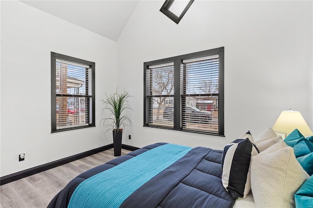 bedroom featuring lofted ceiling, baseboards, and wood finished floors