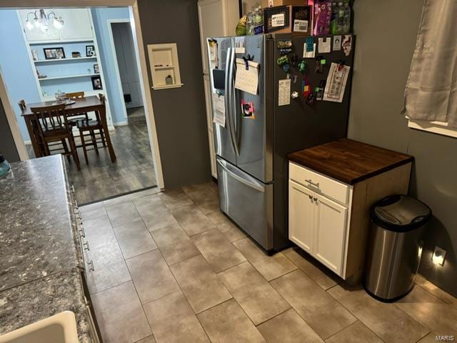 kitchen featuring light tile patterned floors, stainless steel fridge with ice dispenser, and white cabinets