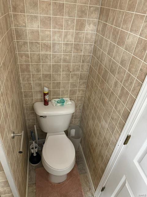 bathroom featuring toilet, tile walls, and tile patterned flooring