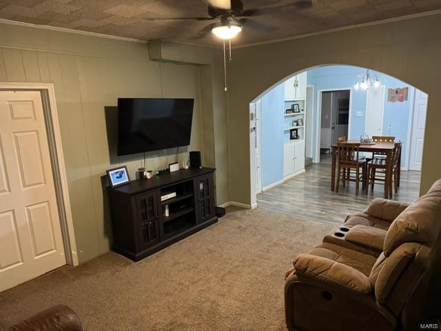 carpeted living room with crown molding and ceiling fan