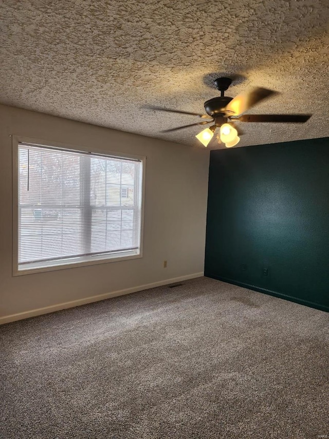 carpeted spare room featuring ceiling fan and a textured ceiling