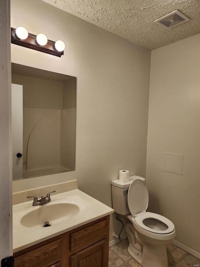 bathroom featuring tile patterned floors, toilet, vanity, and a textured ceiling