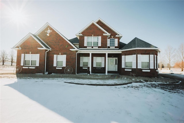 view of front of property featuring covered porch, a shingled roof, and brick siding