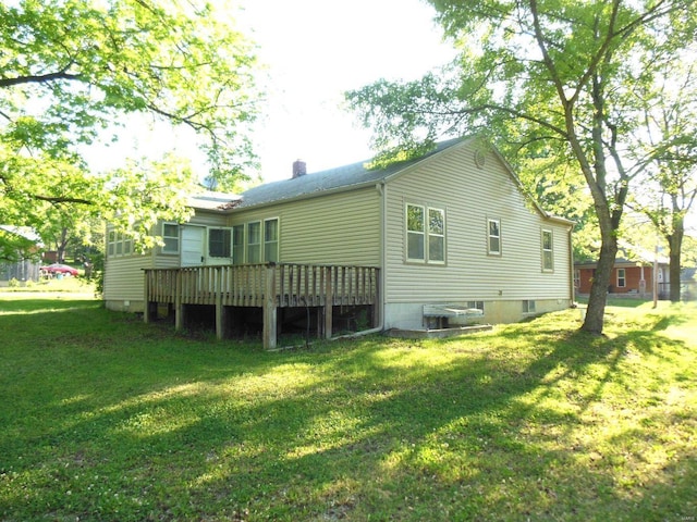 back of property with a lawn, a chimney, and a wooden deck