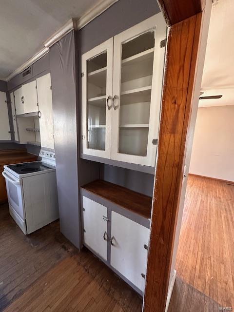 interior space featuring dark countertops, electric range, wood-type flooring, and white cabinets