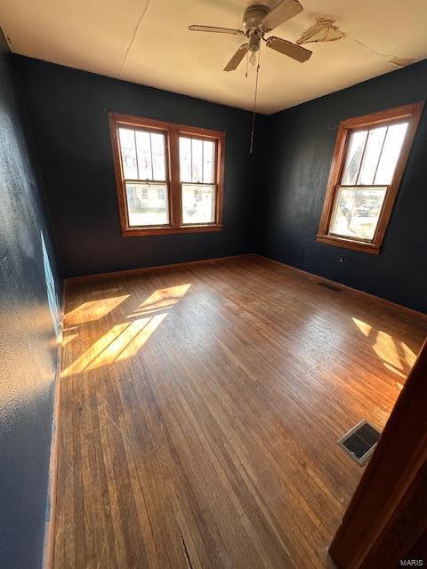 spare room with baseboards, ceiling fan, visible vents, and hardwood / wood-style floors