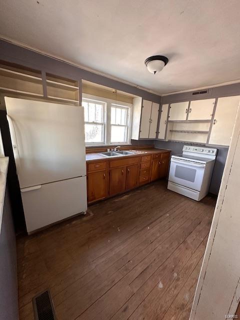 kitchen with white appliances, visible vents, dark wood finished floors, brown cabinets, and a sink