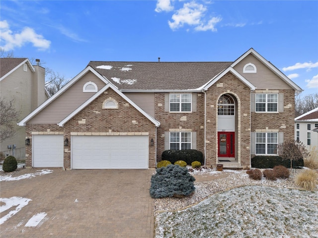 view of front of home featuring brick siding, decorative driveway, and an attached garage